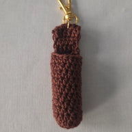 Brown crochet keychain pouch with gold clasp on light gray background