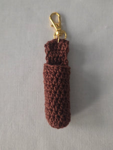 Brown crochet keychain pouch with gold clasp on light gray background