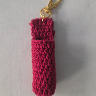Handmade red crochet keychain pouch with gold clasp on light fabric background
