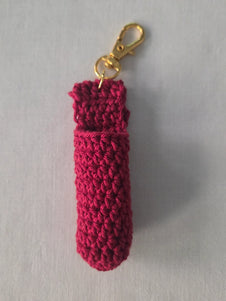 Handmade red crochet keychain pouch with gold clasp on light fabric background
