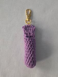Purple crochet chapstick holder with gold keychain clasp on light background