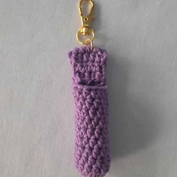 Purple crochet chapstick holder with gold keychain clasp on light background