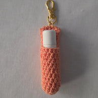 Peach crochet lip balm holder keychain with white tube and gold clasp on white background
