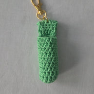 Green crocheted keychain with a gold clasp on a gray background