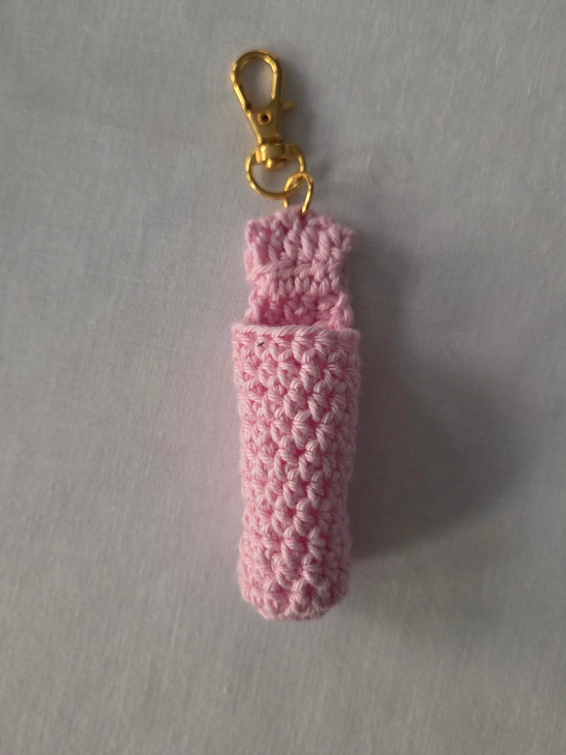 Pink crochet keychain holder with gold clasp on light background