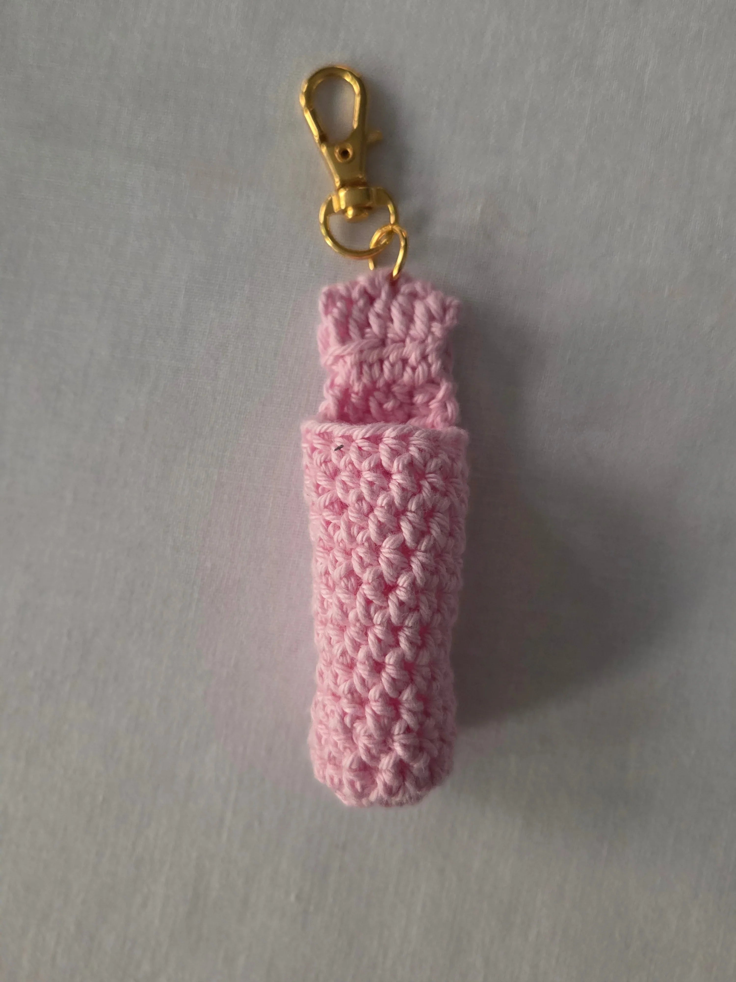 Pink crochet keychain holder with gold clasp on light background