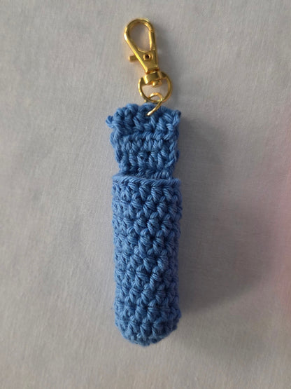 Blue crocheted keychain with a gold clasp on a light gray background