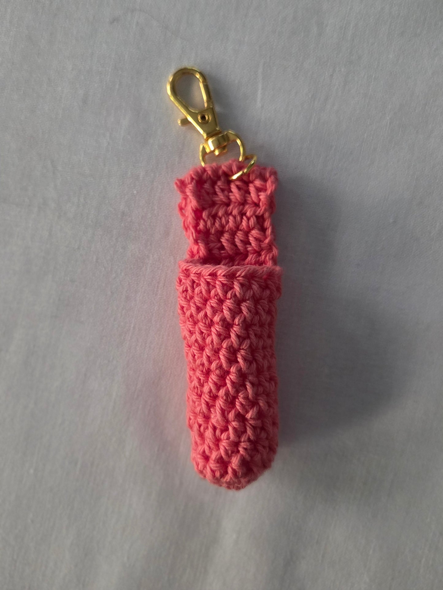 Handmade pink crochet keychain pouch with gold clasp on a light background
