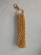 Handmade mustard yellow crochet keychain with gold clasp on white background