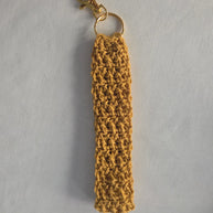 Handmade mustard yellow crochet keychain with gold clasp on white background