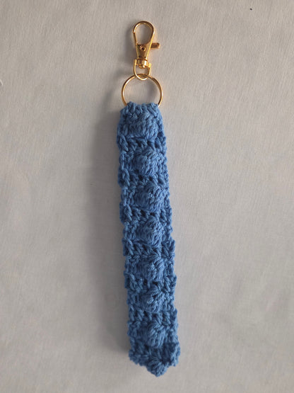 Handmade blue crochet keychain with gold clasp on a light background