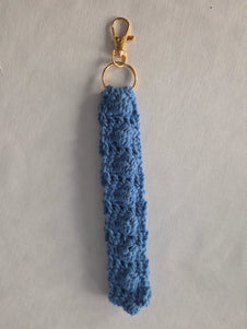 Handmade blue crochet keychain with gold clasp on a light background