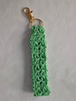 Mint green crochet keychain with gold clasp on light gray background.