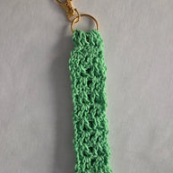 Mint green crochet keychain with gold clasp on light gray background.