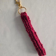 Handmade maroon crochet keychain with gold clasp on light background