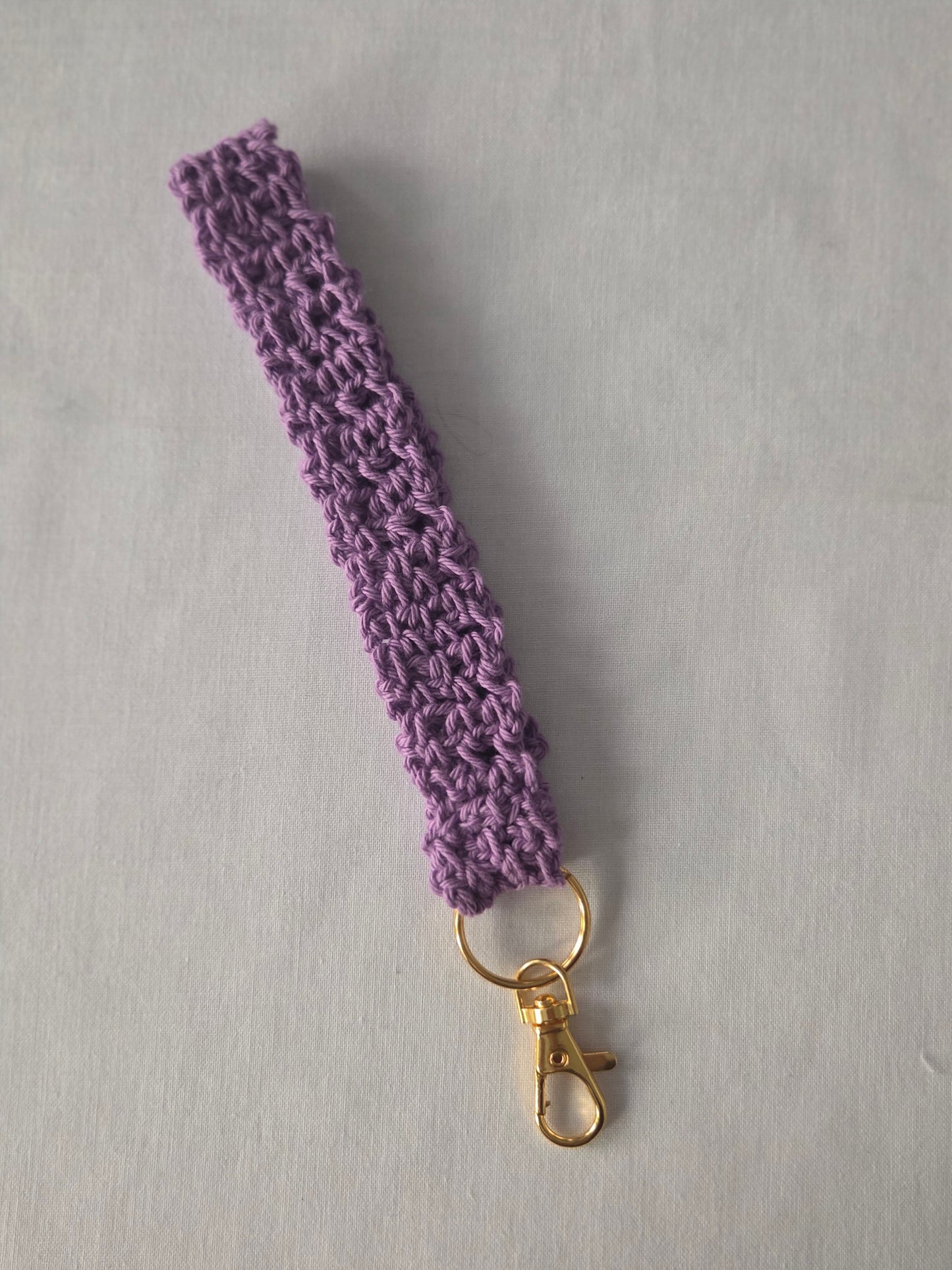Purple crochet keychain wristlet with gold clasp on light background