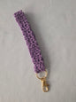 Purple crochet keychain wristlet with gold clasp on light background