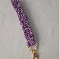 Purple crochet keychain wristlet with gold clasp on light background