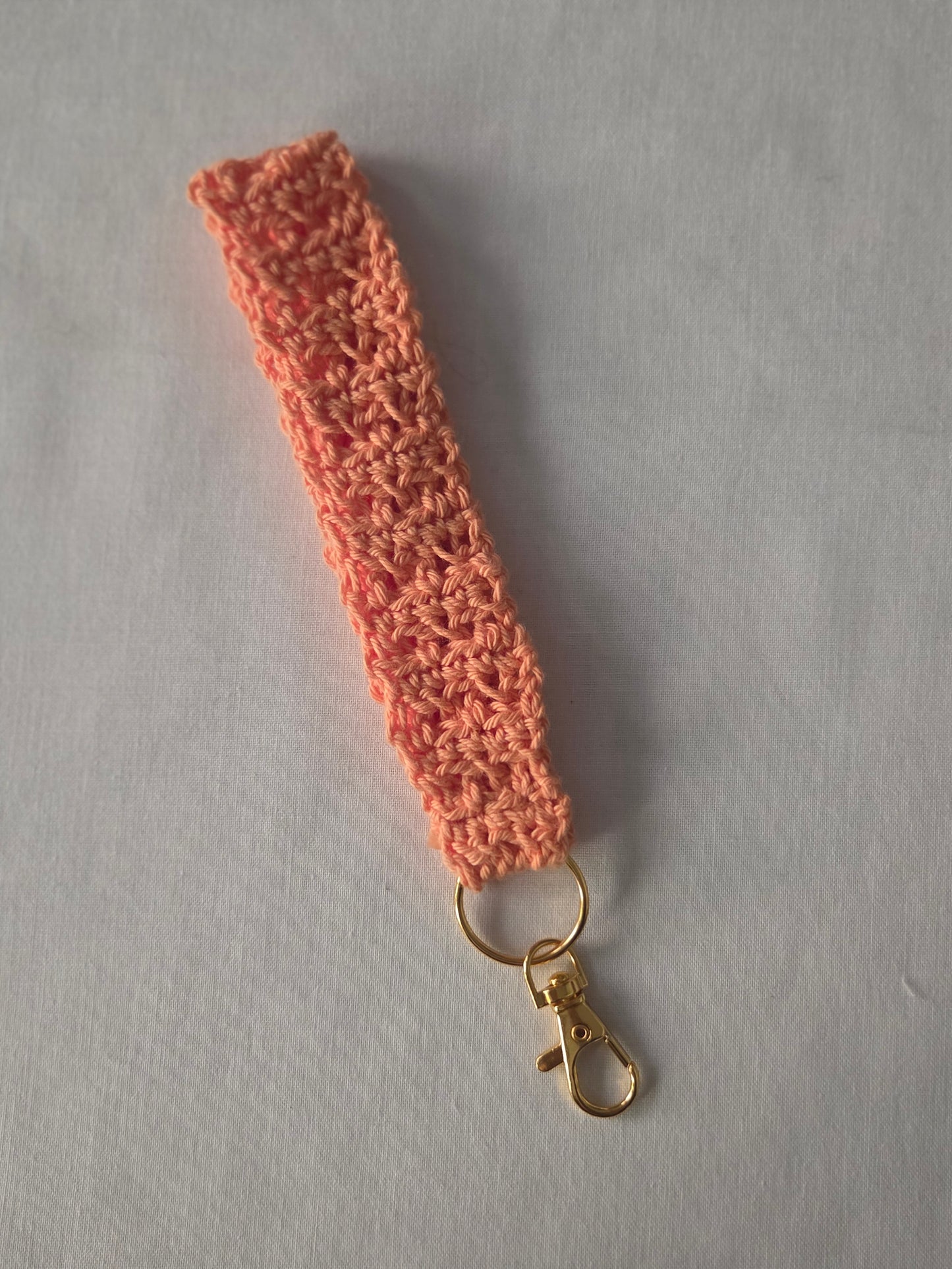 Handmade peach crochet keychain wristlet with gold clasp on white background