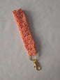 Handmade peach crochet keychain wristlet with gold clasp on white background