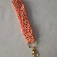 Handmade peach crochet keychain wristlet with gold clasp on white background