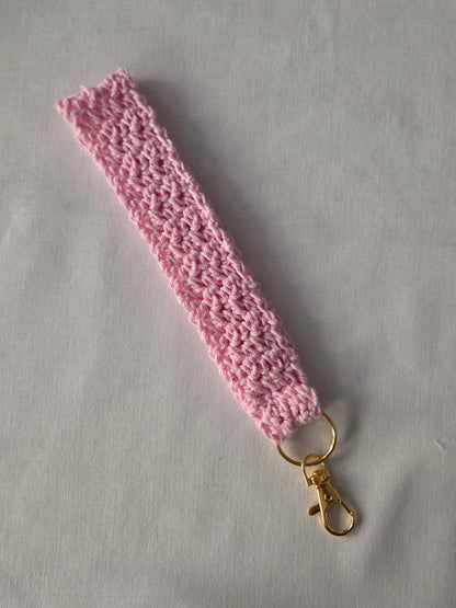 Handmade pink crochet keychain wristlet with gold clasp on white background