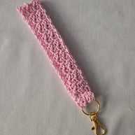 Handmade pink crochet keychain wristlet with gold clasp on white background