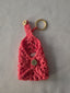 Handmade pink crochet keychain pouch with gold snap button and keyring on light fabric