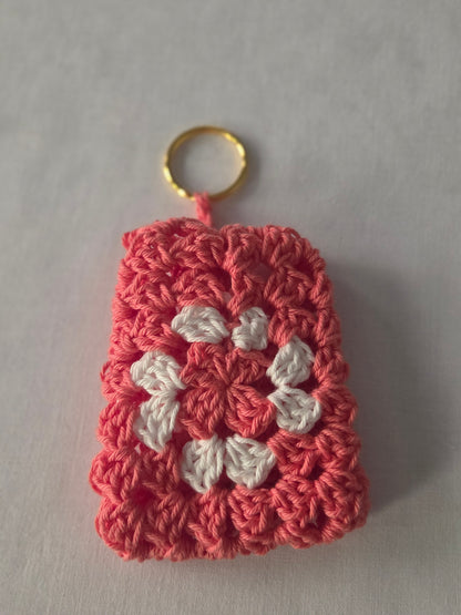 Handmade crochet keychain with pink and white flower pattern on a white background