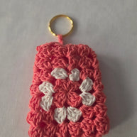 Handmade crochet keychain with pink and white flower pattern on a white background