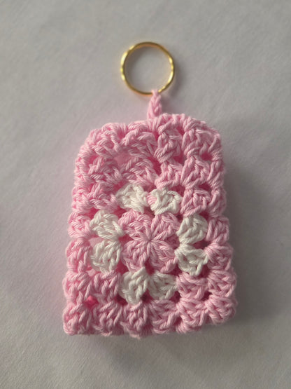Pink and white crochet keychain pouch with gold ring on white background