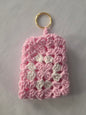 Pink and white crochet keychain pouch with gold ring on white background