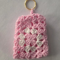Pink and white crochet keychain pouch with gold ring on white background
