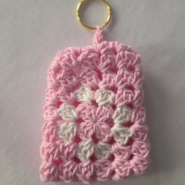 Pink and white crochet keychain pouch with gold ring on white background