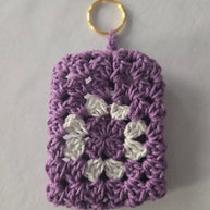Purple and white crochet granny square keychain with gold ring on white background