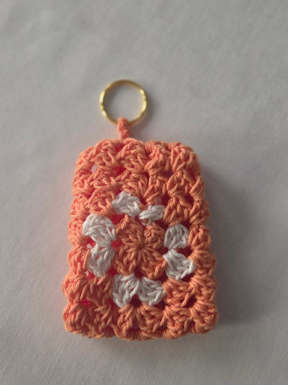 Peach and white crochet granny square keychain on white background