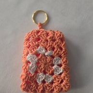 Peach and white crochet granny square keychain on white background