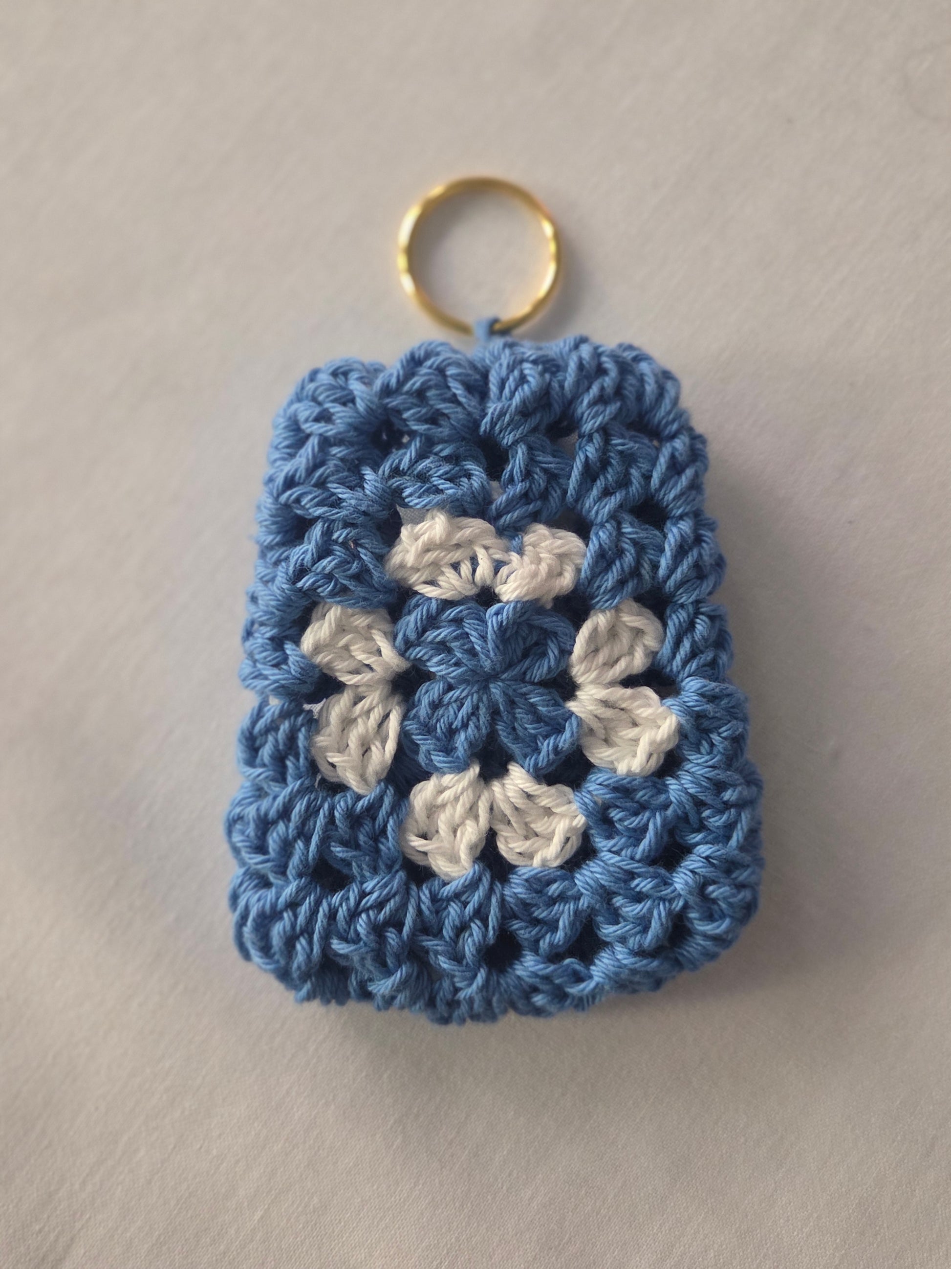 Blue and white crochet granny square keychain on a light background