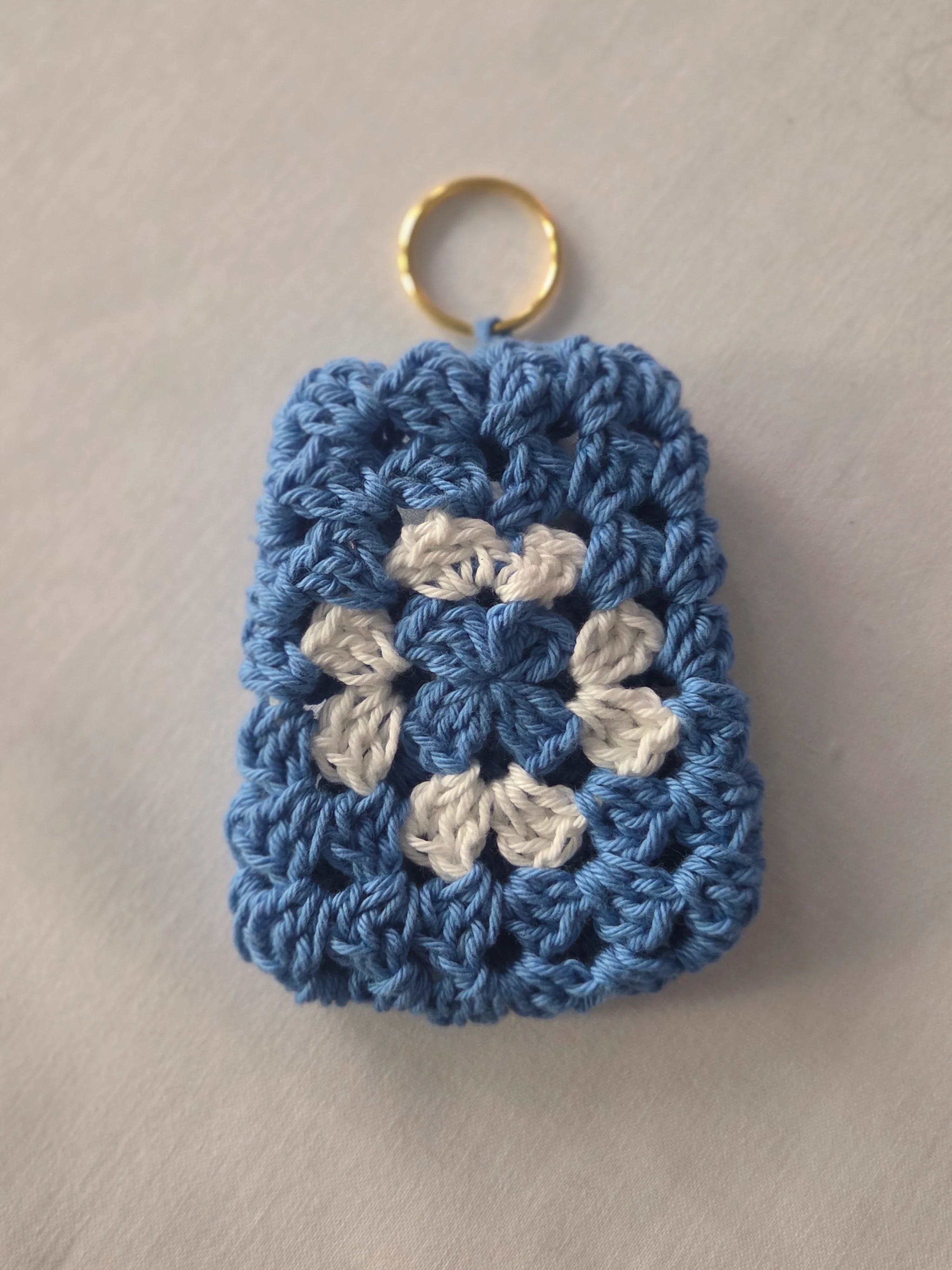 Blue and white crochet granny square keychain on a light background