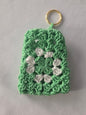 Green and white crochet keychain with granny square pattern on white background