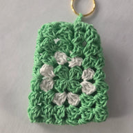 Green and white crochet keychain with granny square pattern on white background