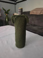 Green crochet wine bottle cover on table with grey couch in background
