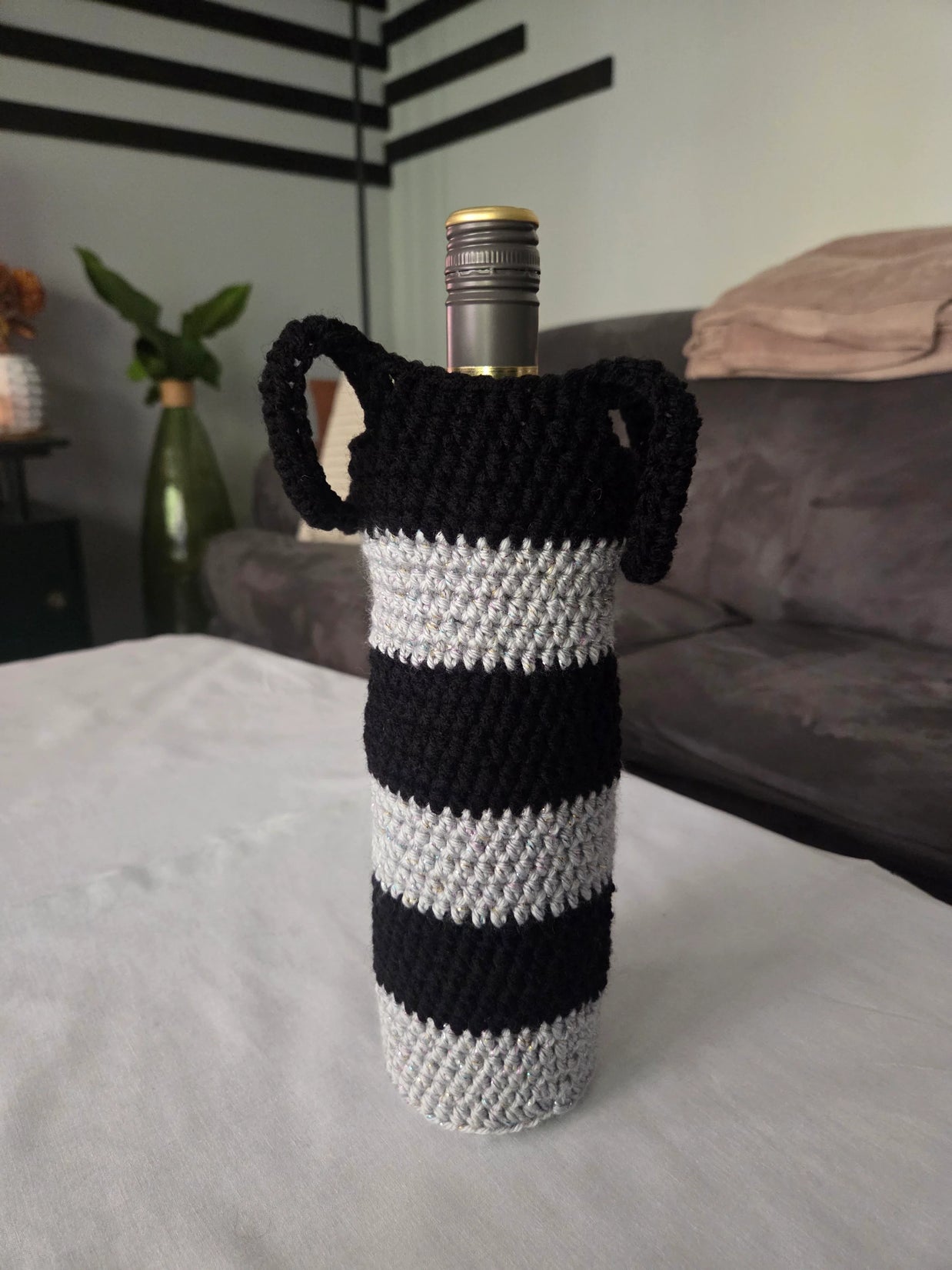 Wine bottle in black and white striped crochet cover on table in modern living room