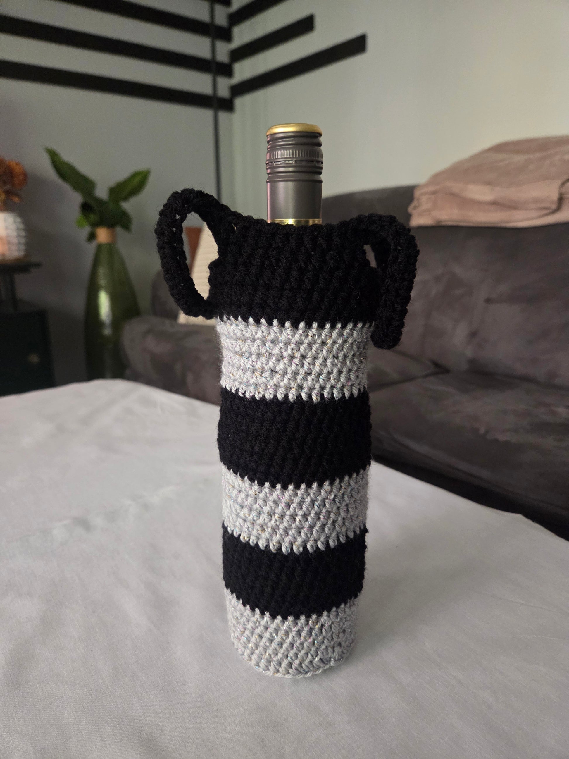 Wine bottle in black and white striped crochet cover on table in modern living room
