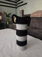 Wine bottle in black and white striped crochet cover on table in modern living room