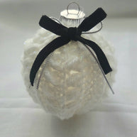 White knitted Christmas ornament with black velvet bow on plain background
