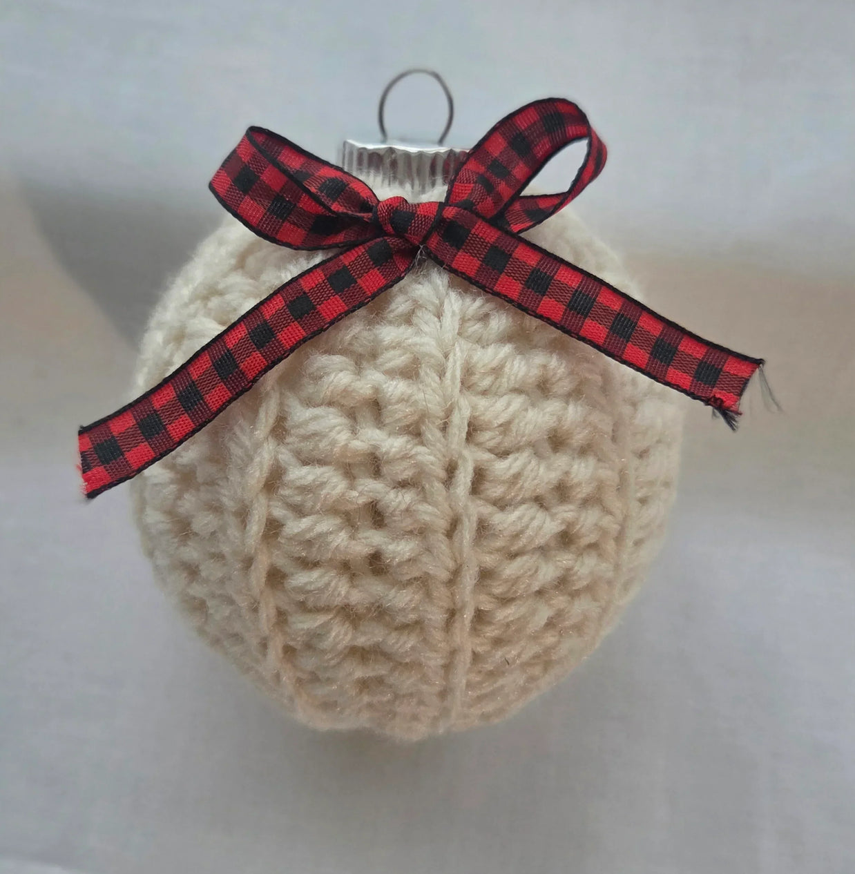 Crocheted cream yarn Christmas ornament with red plaid ribbon bow