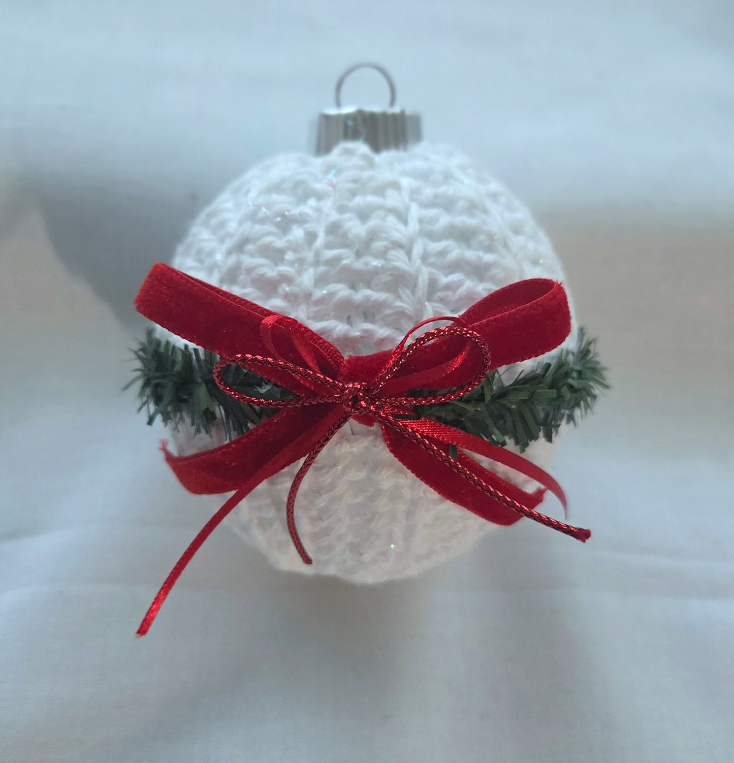 White crochet Christmas ornament with pine garnish and red velvet ribbon bow