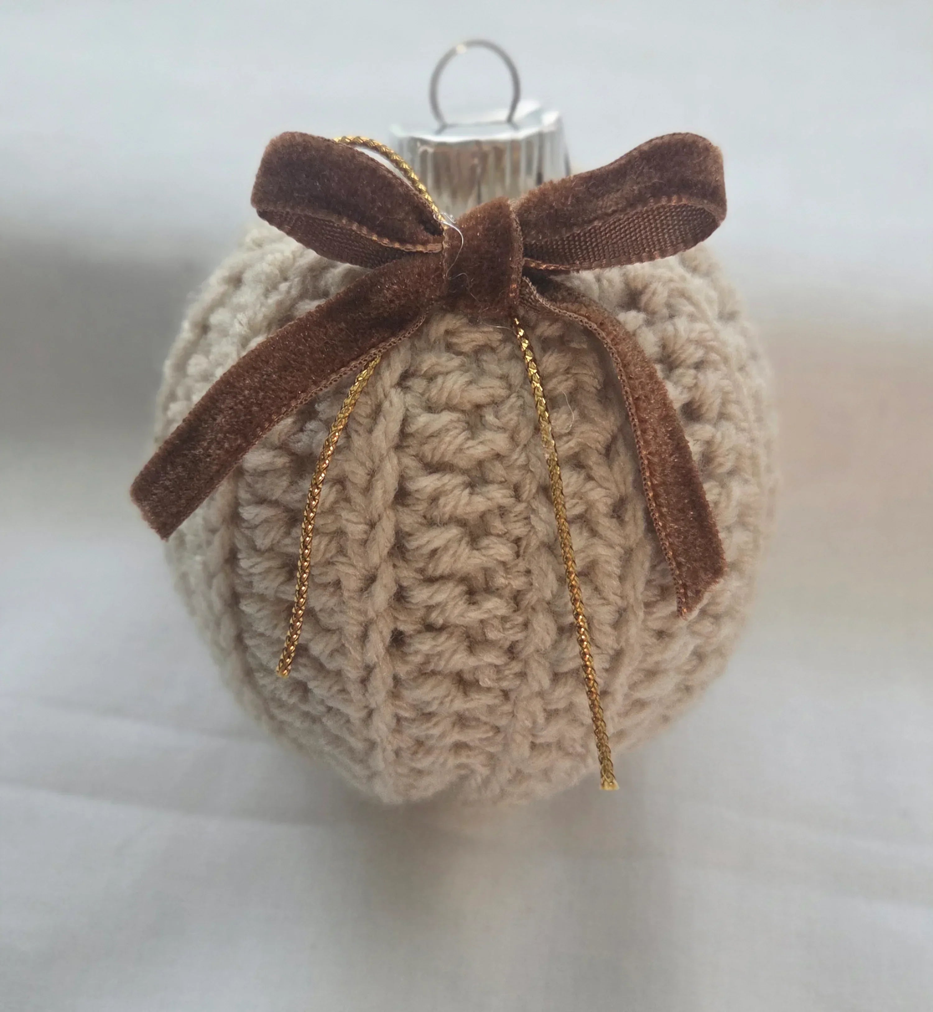 Crocheted Christmas ornament with brown velvet bow on white background