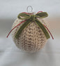 Knitted beige Christmas ornament with green velvet bow and red ribbon on white background